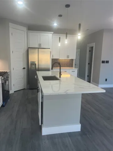 a kitchen with stainless steel appliances granite countertop a sink and a refrigerator