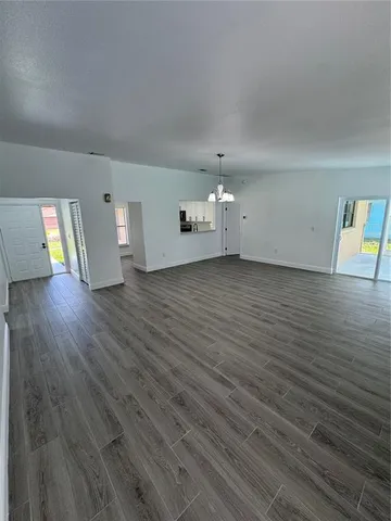 an empty room with wooden floor and chandelier