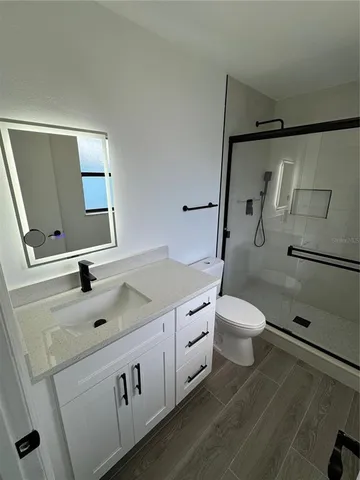 a bathroom with a granite countertop sink toilet and a mirror