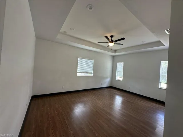 an empty room with wooden floor and ceiling fan