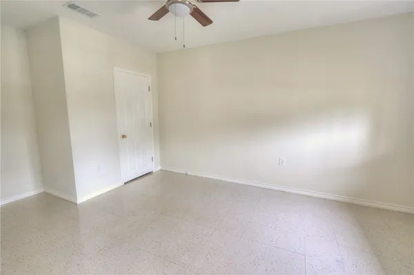 an empty room with a ceiling fan and window