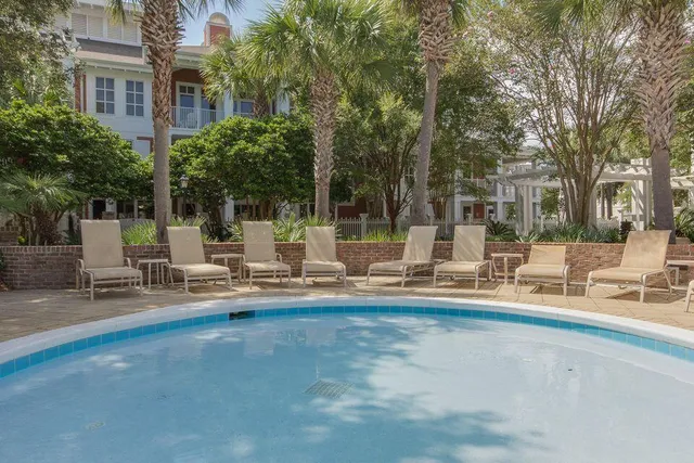 a view of pool with lawn chairs and large trees