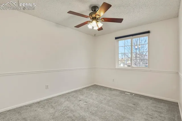 an empty room with a window and a ceiling fan