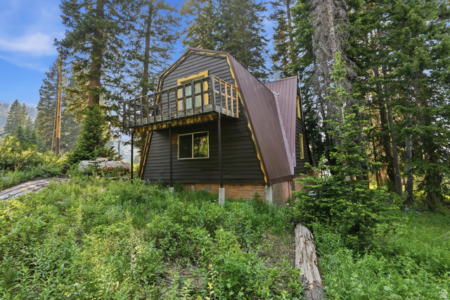 8505 South Snake Crk Road Salt Lake City, UT 84121 - Photo 4 of 67 Dark-toned A-frame structure featuring a metal roof and an elevated balcony with a wood railing