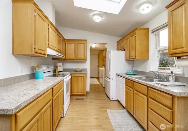 a kitchen with a sink stove cabinets and wooden floor