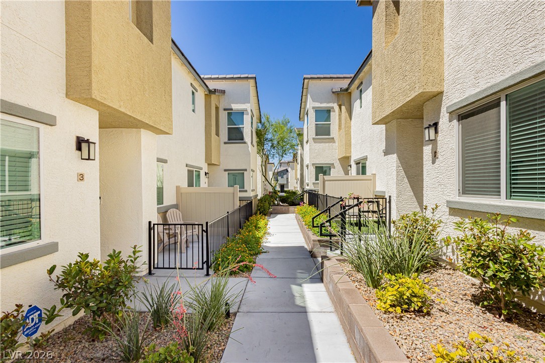12369 Golden Wreath Road, Unit 2 Las Vegas, NV 89183 - Photo 17 of 19 A well-maintained concrete walkway leads between modern multi-story structures featuring private fenced patios and desert-friendly landscaping.