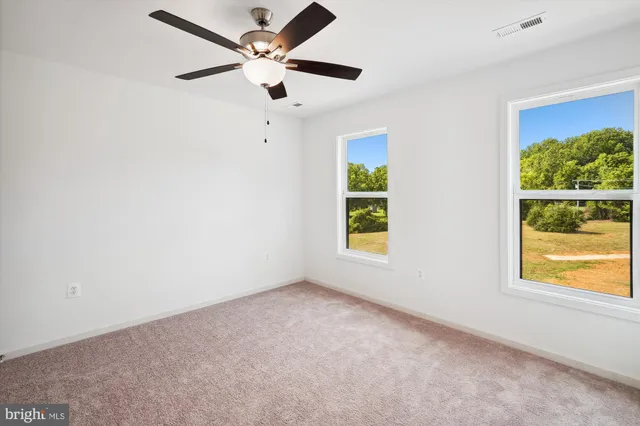 an empty room with windows and fan