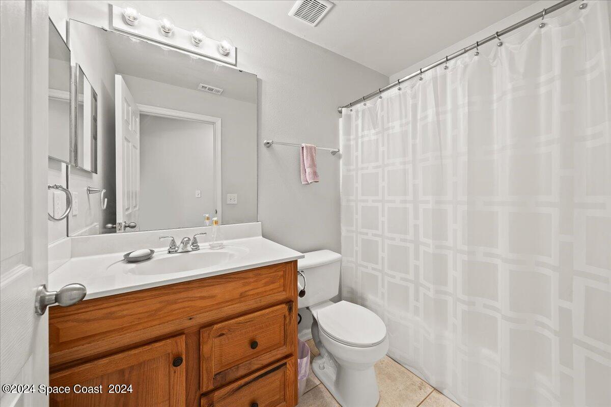 3905 Grand Meadows Boulevard Melbourne, FL 32934 - Photo 18 of 32 a bathroom with a sink a toilet and shower curtain