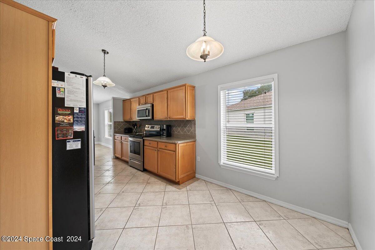3905 Grand Meadows Boulevard Melbourne, FL 32934 - Photo 10 of 32 a kitchen with stainless steel appliances granite countertop a stove a sink and a refrigerator