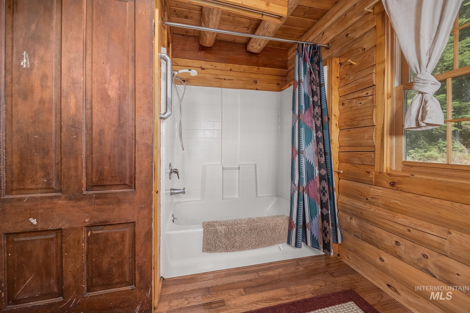 2150 Seid Creek Road Cambridge, ID 83610 - Photo 39 of 50 Bathroom featuring a white tub and shower combination with an accessible grab bar, surrounded by natural wood paneled walls