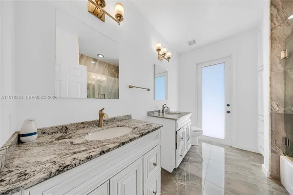 a bathroom with a granite countertop double vanity and a mirror