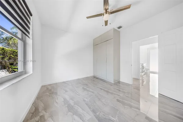 a view of empty room with wooden floor and fan