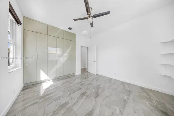a view of empty room with wooden floor and fan