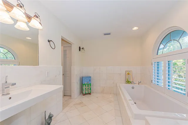 a bathroom with a tub sink and mirror
