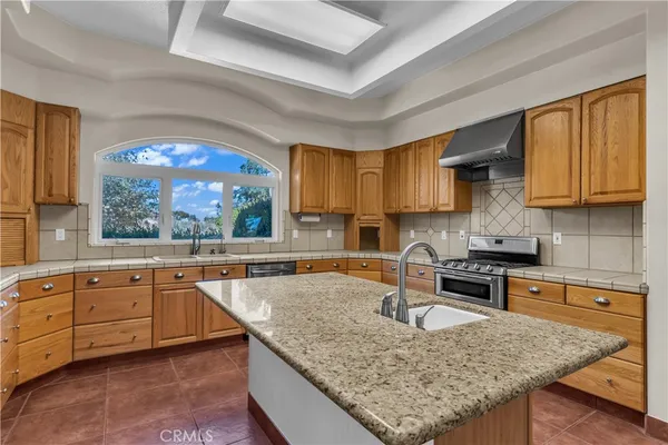 a kitchen with granite countertop a stove a sink and white cabinets