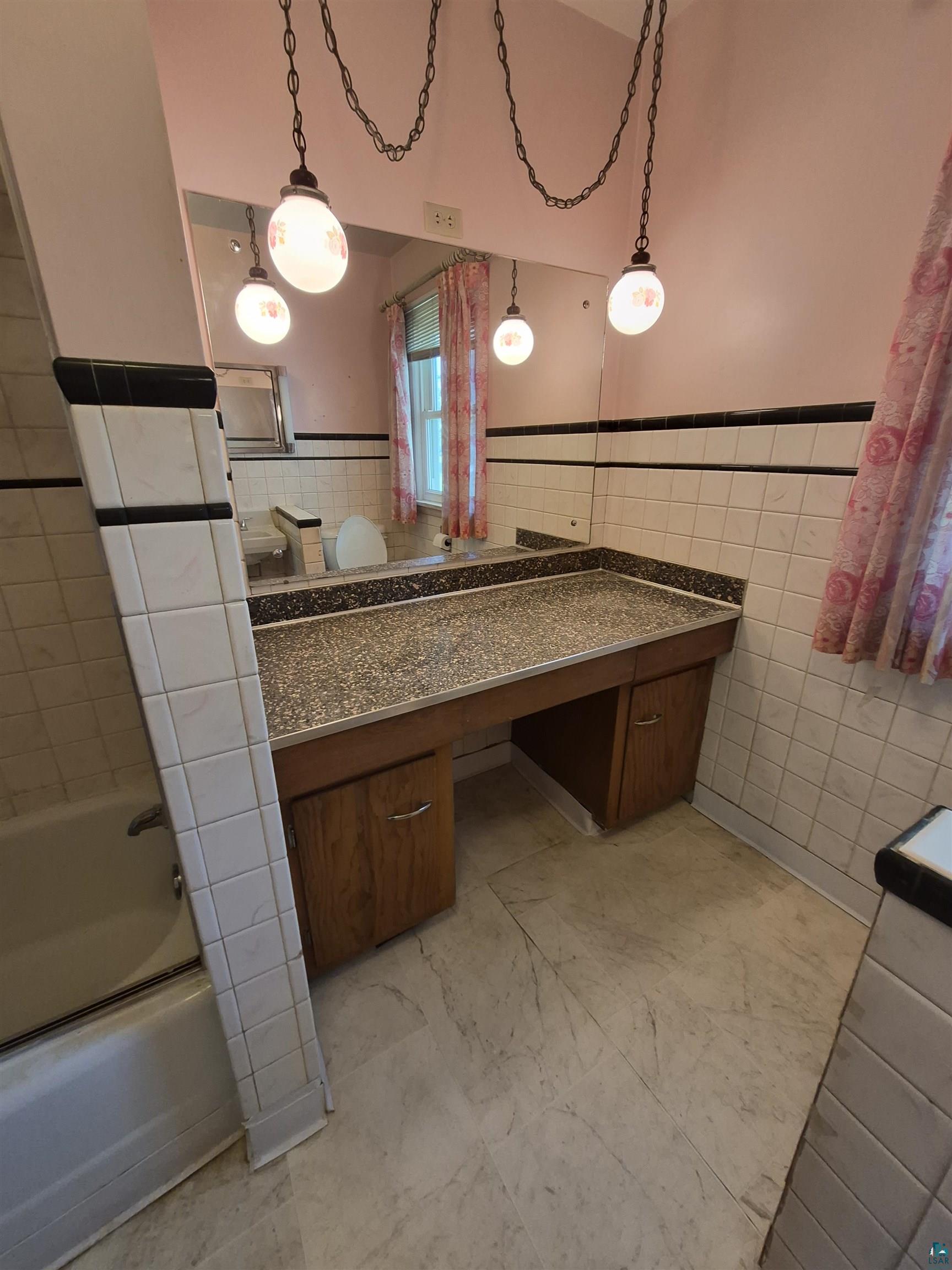 2109 West 22nd Street Duluth, MN 55811 - Photo 12 of 29 Bathroom vanity with a speckled countertop, integrated mirror, and wood-finish cabinetry