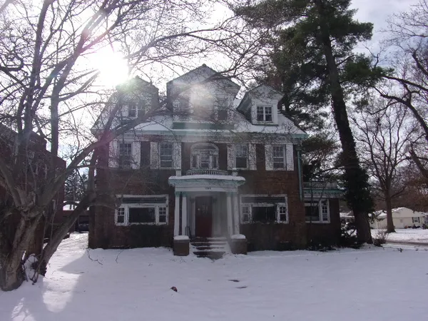 a front view of a house with a yard covered with snow
