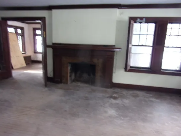 an empty room with windows and fireplace