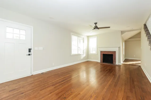 an empty room with wooden floor a fireplace and windows
