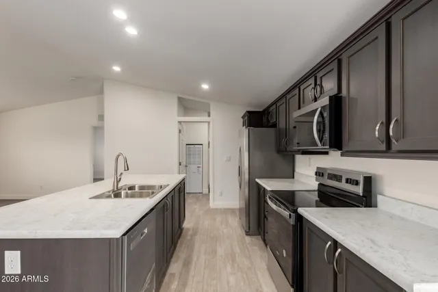 a kitchen with stainless steel appliances granite countertop a sink a refrigerator and a stove