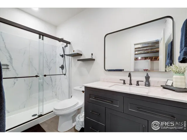 a bathroom with a granite countertop sink toilet a mirror and shower