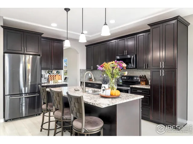 a kitchen with stainless steel appliances kitchen island granite countertop a refrigerator a stove a microwave oven with a dining table and chairs