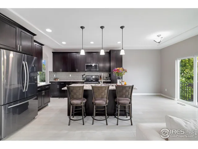 a kitchen with stainless steel appliances kitchen island granite countertop a refrigerator a stove a sink a dining table and chairs with wooden floor