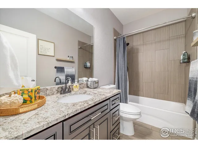 a bathroom with a granite countertop sink a toilet a mirror and shower