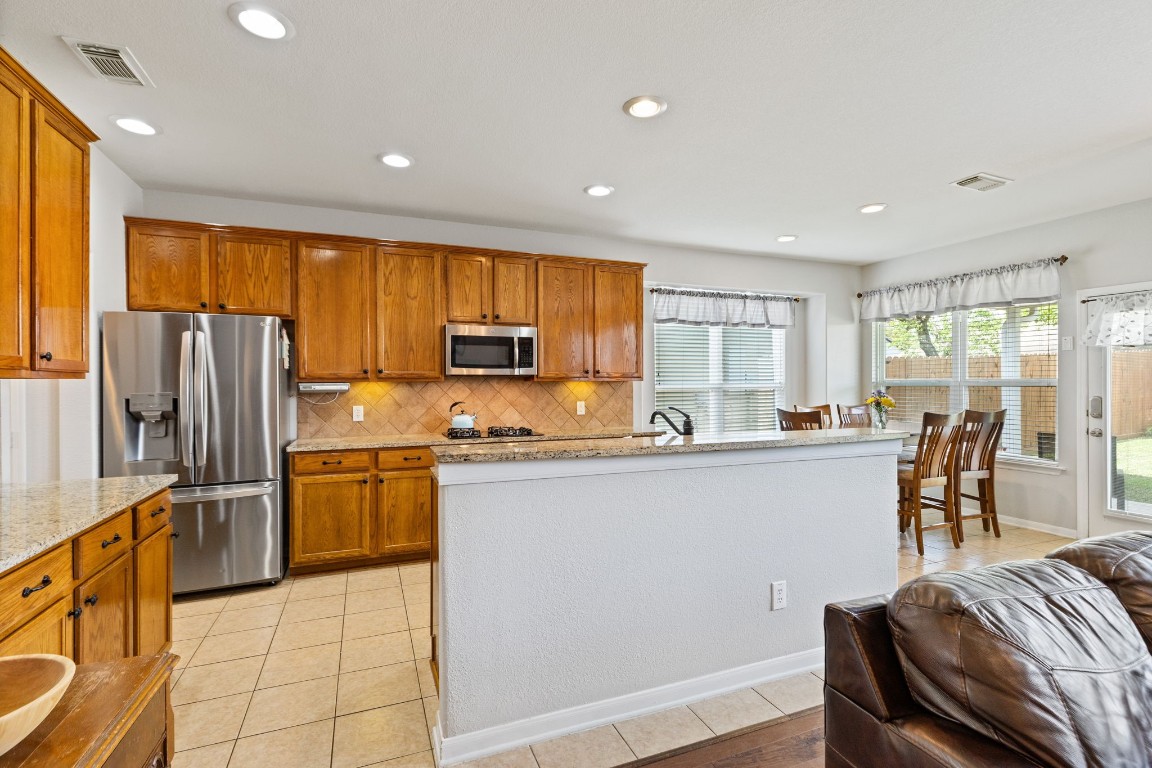 5318 Wisteria Brook Lane Spring, TX 77379 - Photo 19 of 50 a kitchen with stainless steel appliances granite countertop a refrigerator a stove a sink a dining table and chairs with wooden floor