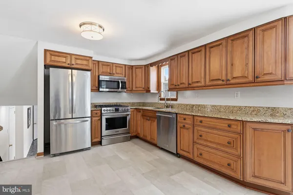 a kitchen with granite countertop a refrigerator stove top oven a sink and dishwasher with wooden floor