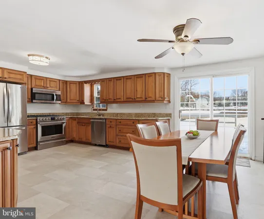 a kitchen with stainless steel appliances granite countertop a sink a stove a refrigerator with a dining table and chairs