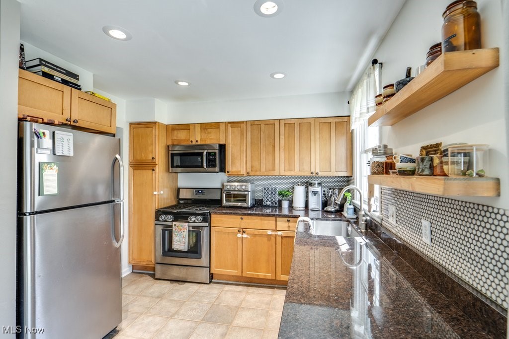 5284 Bridgewater Road Cleveland, OH 44124 - Photo 9 of 22 Kitchen with appliances with stainless steel finishes, dark stone countertops, backsplash, light tile patterned floors, and sink