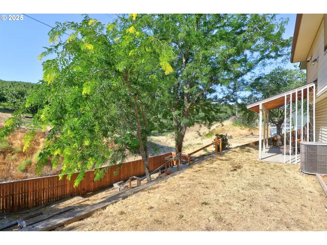 a view of a backyard with wooden fence and large trees