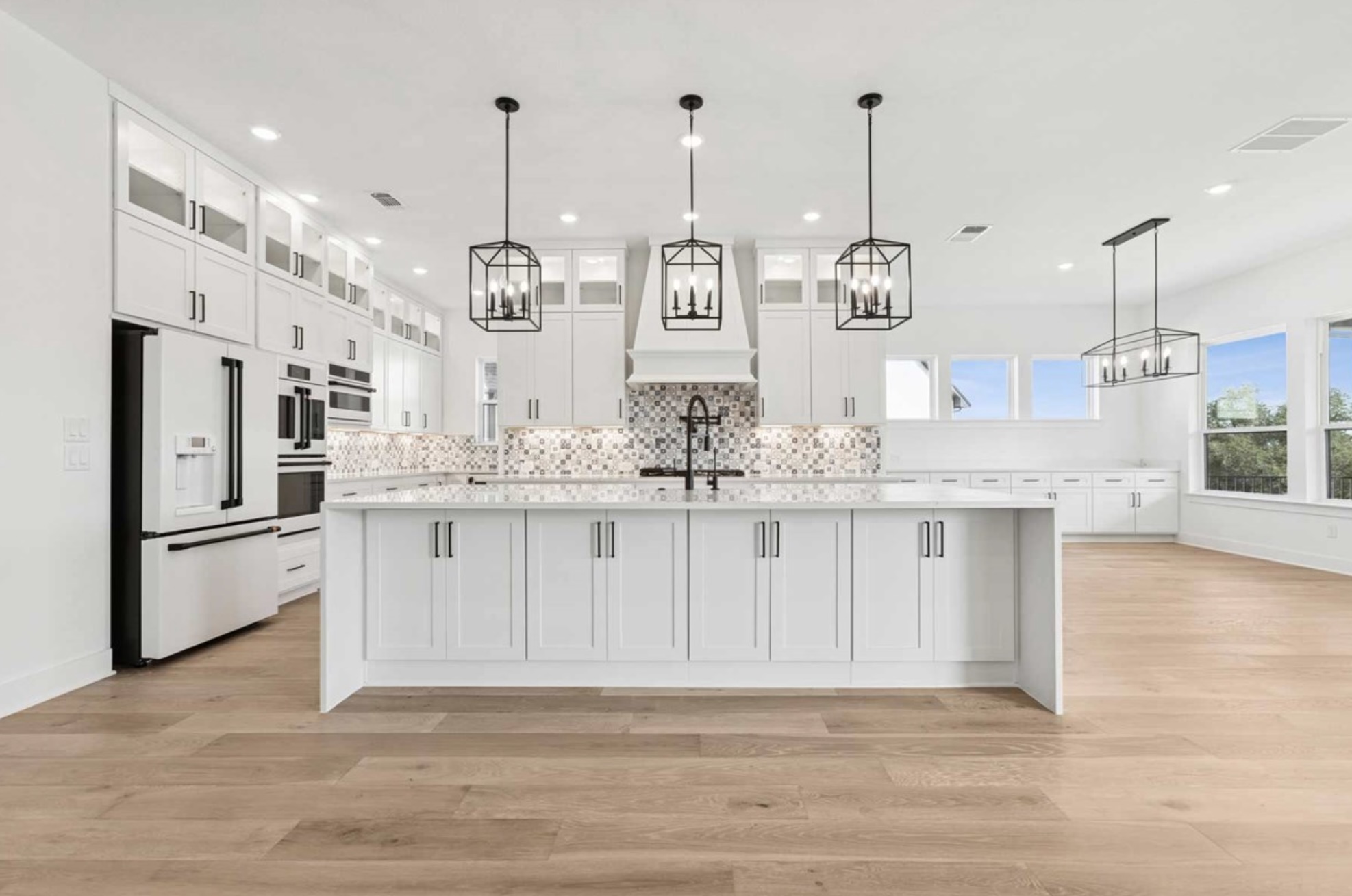 439 Vail River Road Dripping Springs, TX 78620 - Photo 2 of 20 a kitchen with stainless steel appliances kitchen island granite countertop a refrigerator a oven and white cabinets with wooden floor