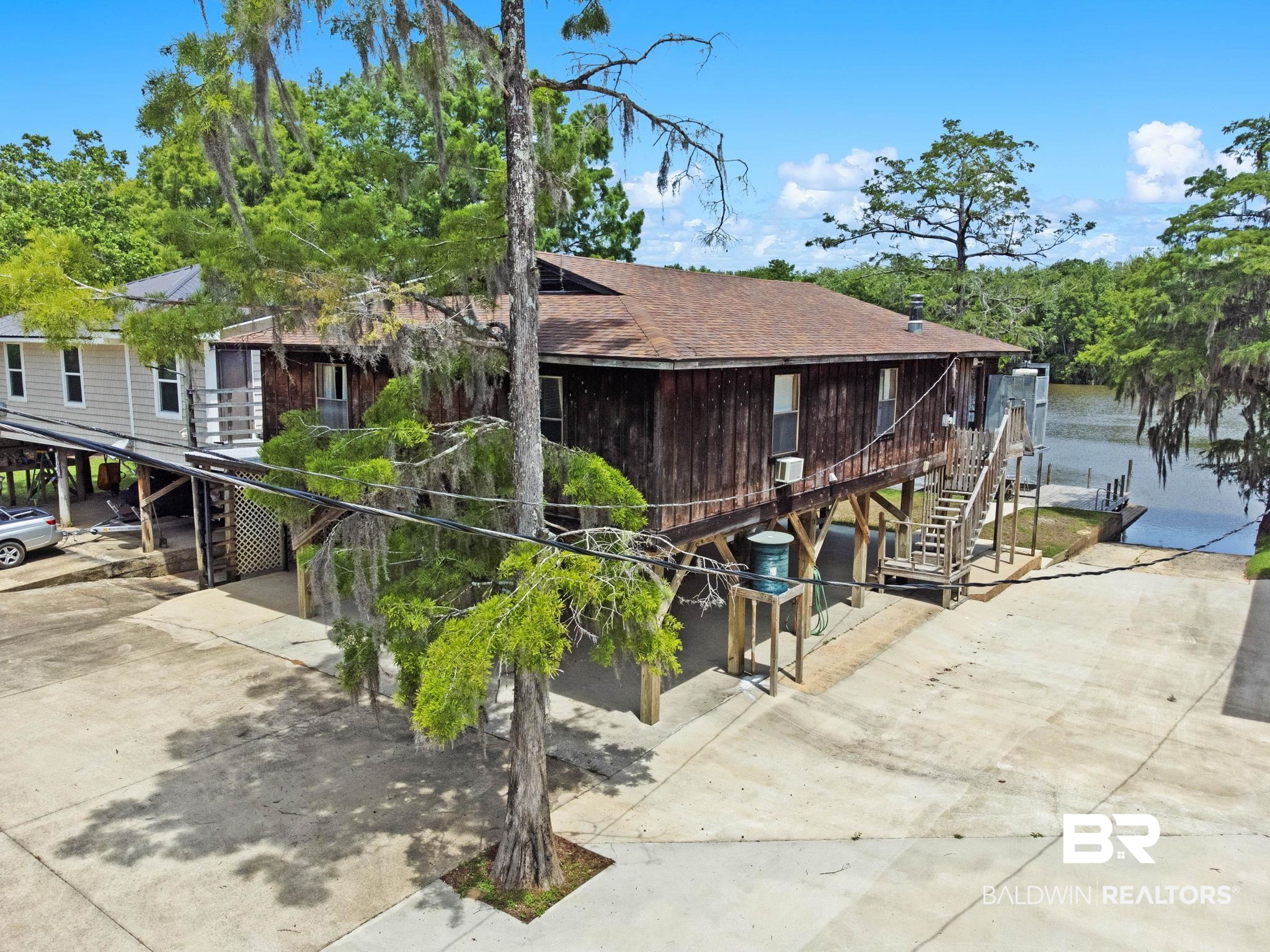 8153 Bryant's Lndg Road Stockton, AL 36579 - Photo 7 of 87 Elevated wood-sided residence featuring a sloped brown shingle roof and multiple windows
