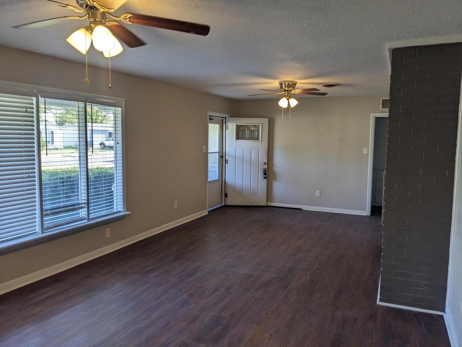 4009 44th Street Lubbock, TX 79413 - Photo 2 of 15 an empty room with wooden floor fan and windows