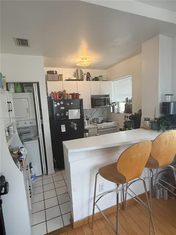 a kitchen with stainless steel appliances a refrigerator a sink a stove a dining table and chairs