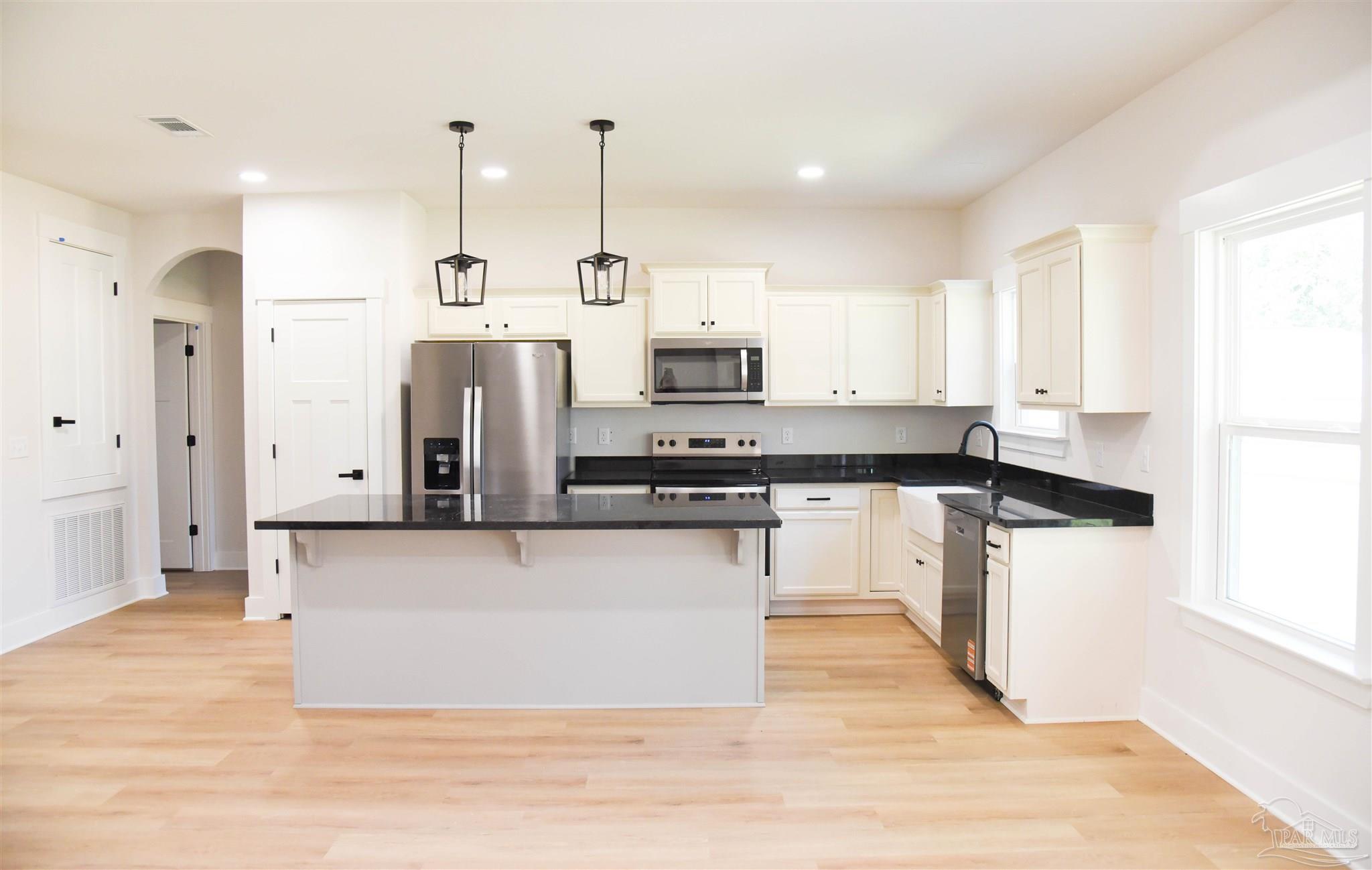 8080 Pinus Lane Pensacola, FL 32534 - Photo 8 of 25 a kitchen with stainless steel appliances kitchen island granite countertop a refrigerator a oven and white cabinets with wooden floor