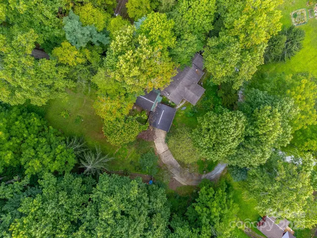 an aerial view of residential house with outdoor space and trees all around