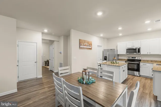 a kitchen with stainless steel appliances a dining table chairs stove refrigerator and cabinets