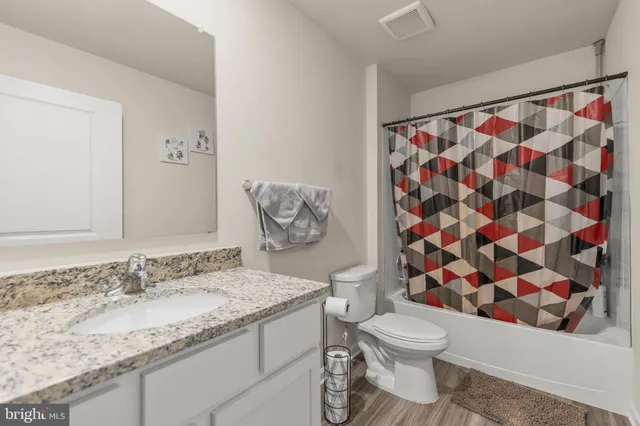 a bathroom with a granite countertop toilet a sink and a shower curtain