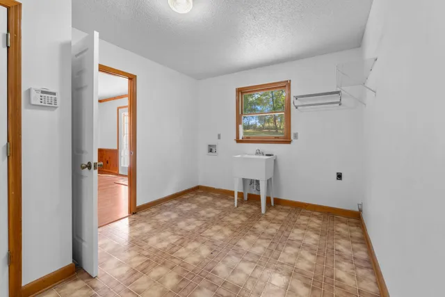 a house that is sitting in the grass with large trees and plants