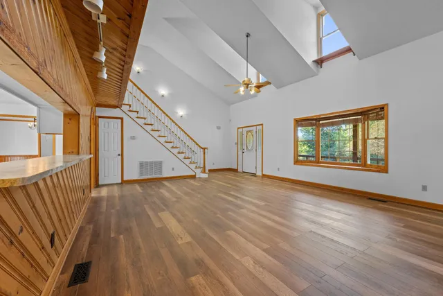 a view of an empty room with wooden floor and a window