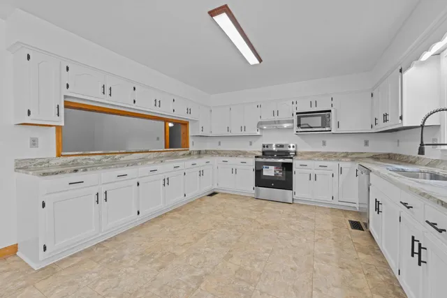 a kitchen with white cabinets white stainless steel appliances and sink