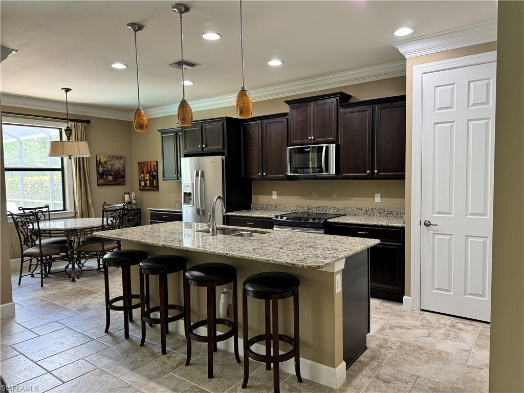 10840 Rutherford Road Fort Myers, FL 33913 - Photo 19 of 35 Kitchen featuring a kitchen bar, stainless steel appliances, a center island with sink, sink, and decorative light fixtures