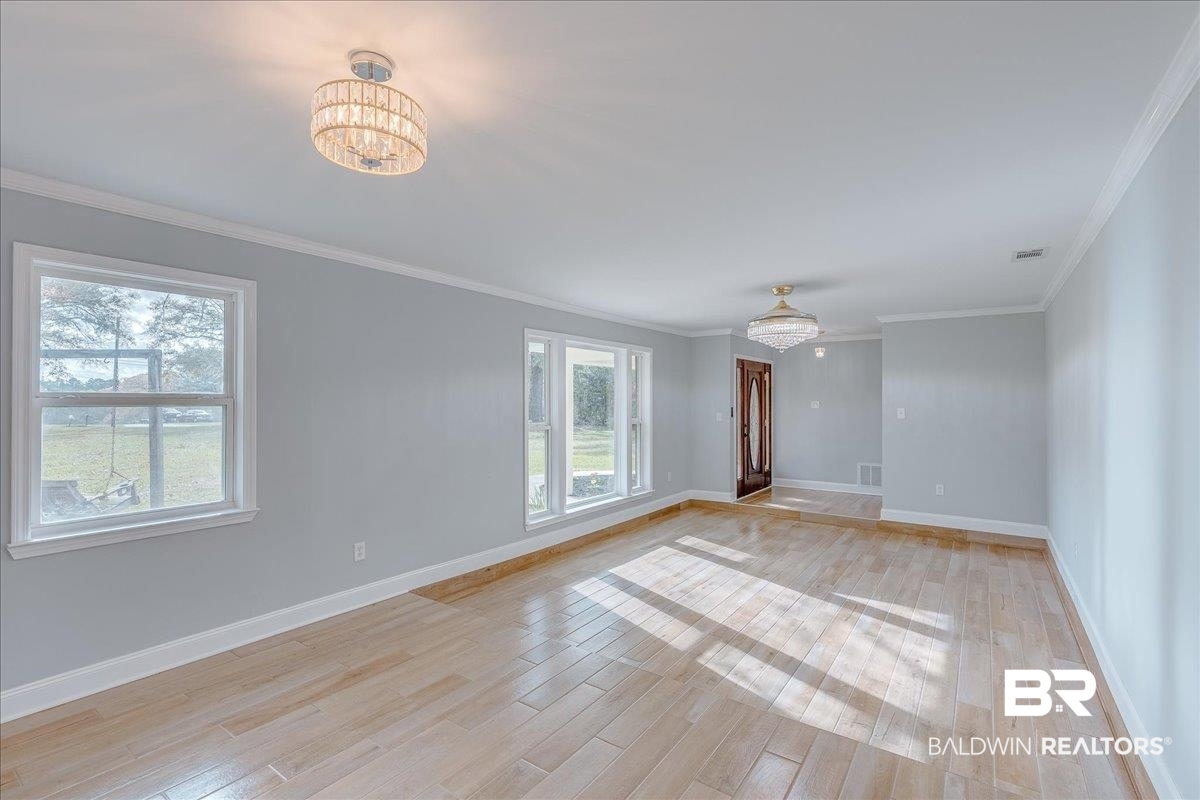 440 Dykes Road Mobile, AL 36608 - Photo 6 of 49 Unfurnished room with ornamental molding, baseboards, light wood finished floors, and a chandelier