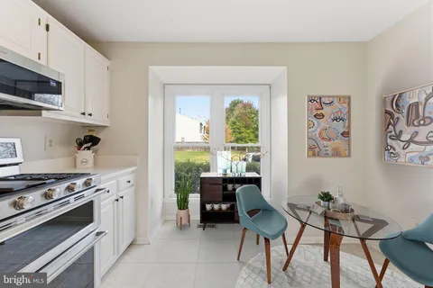 a kitchen with stainless steel appliances a stove a table and chairs in it