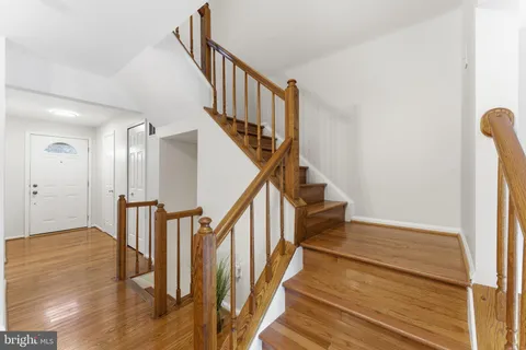 a view of a hallway with wooden floor and a bathroom