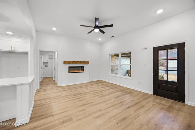 a view of an empty room with a window and a kitchen
