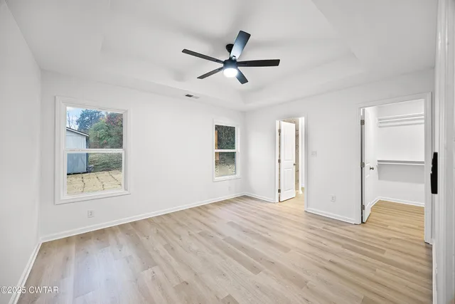 a view of empty room with wooden floor and fan